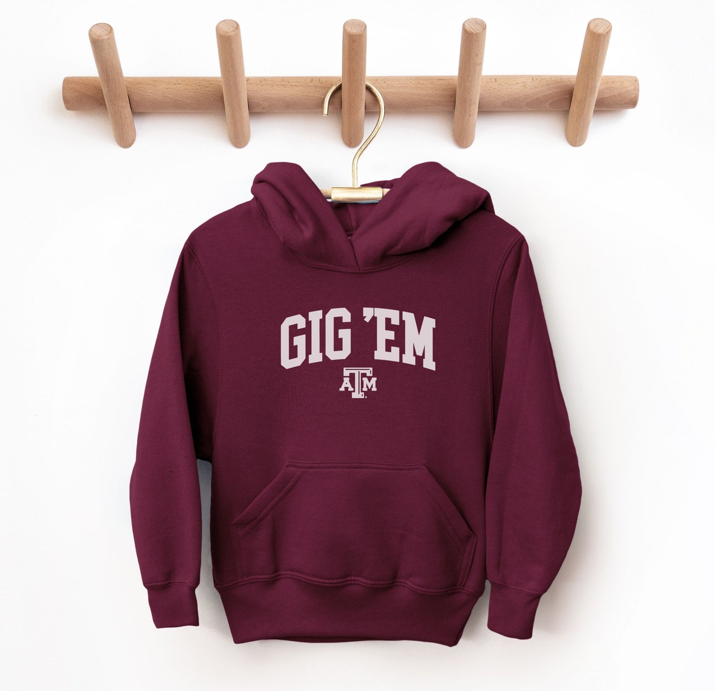 The Maroon Youth Unisex Texas A&M Gig 'Em Collegiate Hooded Sweatshirt lays flat on a white background. The ﻿Texas A&M Gig 'Em Collegiate﻿ graphic is in bold White in a Collegiate style.