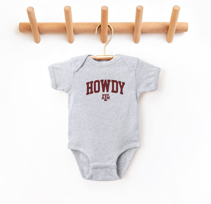 The Heather Grey Infant Unisex Texas A&M Howdy Varsity Bodysuit lays flat on a white background. The ﻿Texas A&M Howdy Varsity﻿ graphic is in bold Maroon in a Collegiate style.