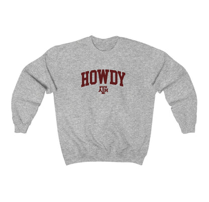 The Sport Grey Adult Unisex Texas A&M Howdy Varsity Crewneck Sweatshirt lays flat on a white background. The ﻿Texas A&M Howdy Varsity﻿ graphic is in bold Maroon in a Collegiate style.