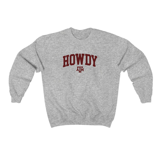 The Sport Grey Adult Unisex Texas A&M Howdy Varsity Crewneck Sweatshirt lays flat on a white background. The ﻿Texas A&M Howdy Varsity﻿ graphic is in bold Maroon in a Collegiate style.