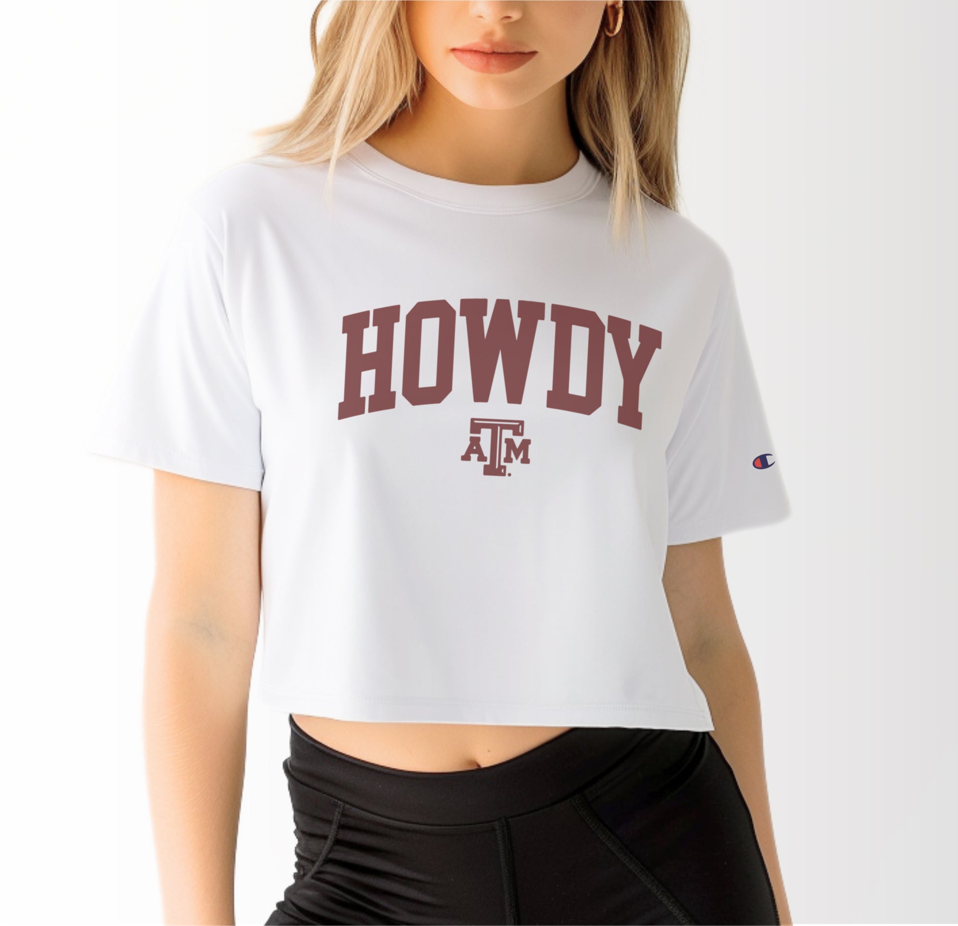 A model wears the White Adult Womens Texas A&M Howdy Varsity Crop Top.  The ﻿Texas A&M Howdy Varsity﻿ graphic is in bold Maroon in a Collegiate style.