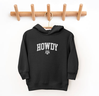 The Black Toddler Unisex Texas A&M Howdy Varsity Hooded Sweatshirt lays flat on a white background. The ﻿Texas A&M Howdy Varsity﻿ graphic is in bold White in a Collegiate style.