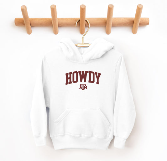 The White Youth Unisex Texas A&M Howdy Varsity Hooded Sweatshirt lays flat on a white background. The ﻿Texas A&M Howdy Varsity﻿ graphic is in bold Maroon in a Collegiate style.