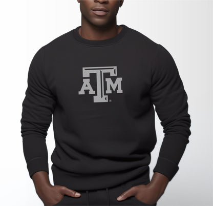 A model wears the Black Adult Unisex Texas A&M Logo Crewneck Sweatshirt.  The ﻿Texas A&M Logo﻿ graphic is in bold White in a Varsity style.