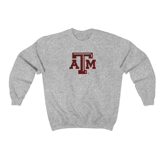 The Sport Grey Adult Unisex Texas A&M Logo Crewneck Sweatshirt lays flat on a white background. The ﻿Texas A&M Logo﻿ graphic is in bold Maroon in a Varsity style.