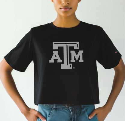 A model wears the Black Adult Womens Texas A&M Logo Crop Top. The ﻿Texas A&M Logo﻿ graphic is in bold white in a Varsity style.