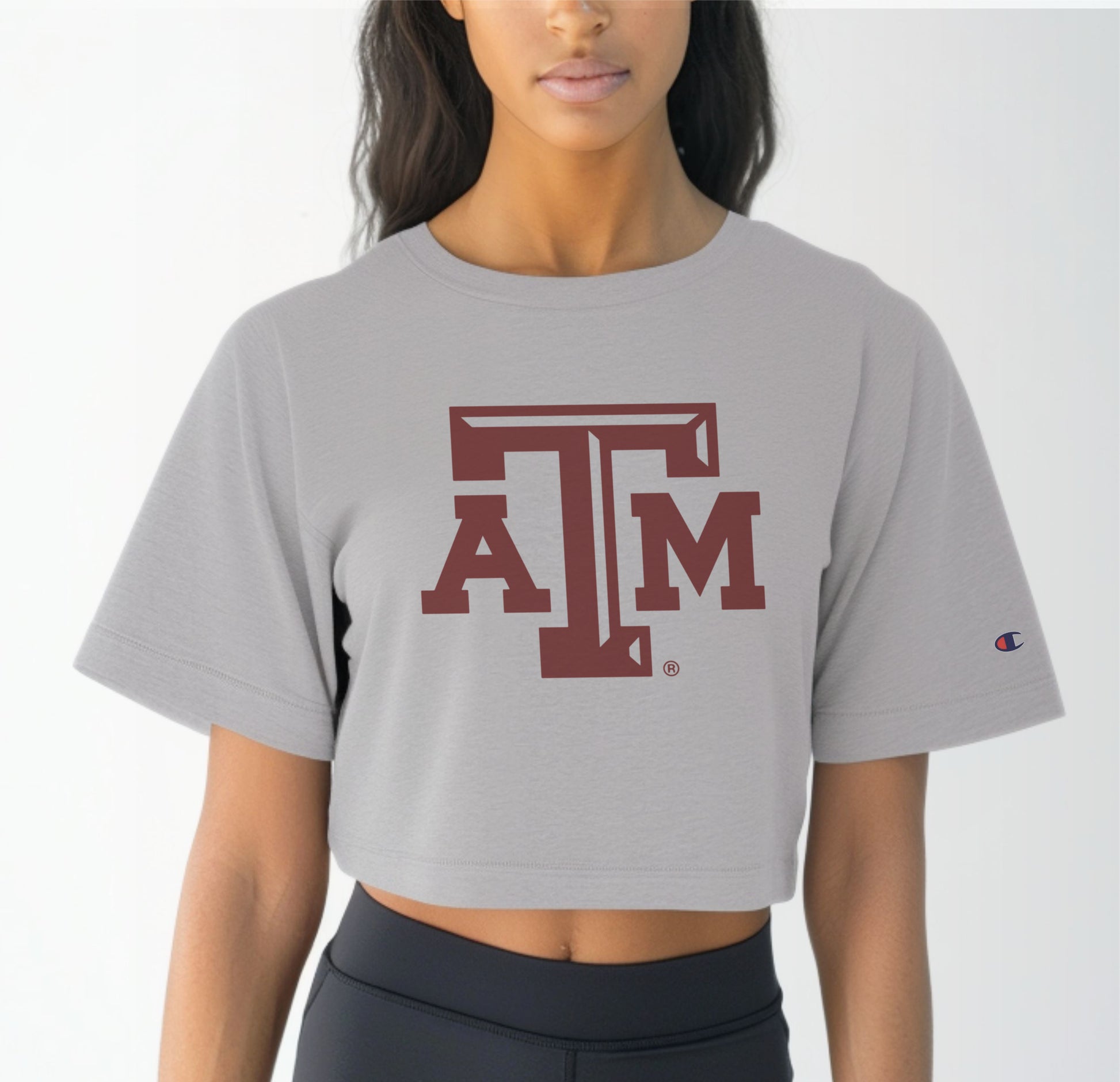 A model wears the Oxford Grey Adult Womens Texas A&M Logo Crop Top.  The ﻿Texas A&M Logo﻿ graphic is in bold Maroon in a Varsity style.