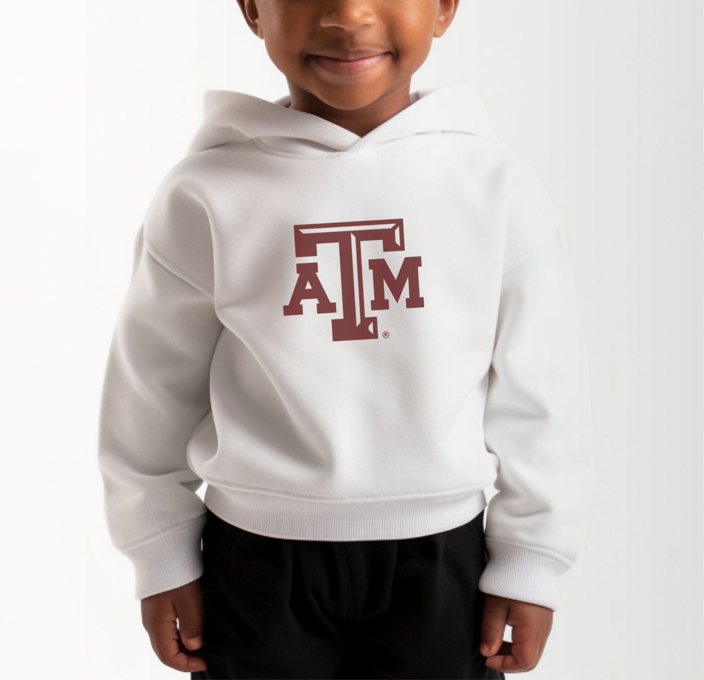 A model wears the White Toddler Unisex Texas A&M Logo Hooded Sweatshirt.  The ﻿Texas A&M Logo﻿ graphic is in bold Maroon in a Varsity style.