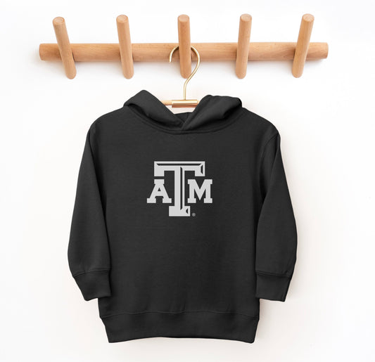 The Black Toddler Unisex Texas A&M Logo Hooded Sweatshirt lays flat on a white background. The ﻿Texas A&M Logo﻿ graphic is in bold White in a Varsity style.