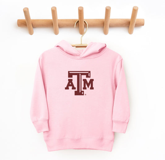 The Pink Toddler Unisex Texas A&M Logo Hooded Sweatshirt lays flat on a white background. The ﻿Texas A&M Logo﻿ graphic is in bold White in a Varsity style.