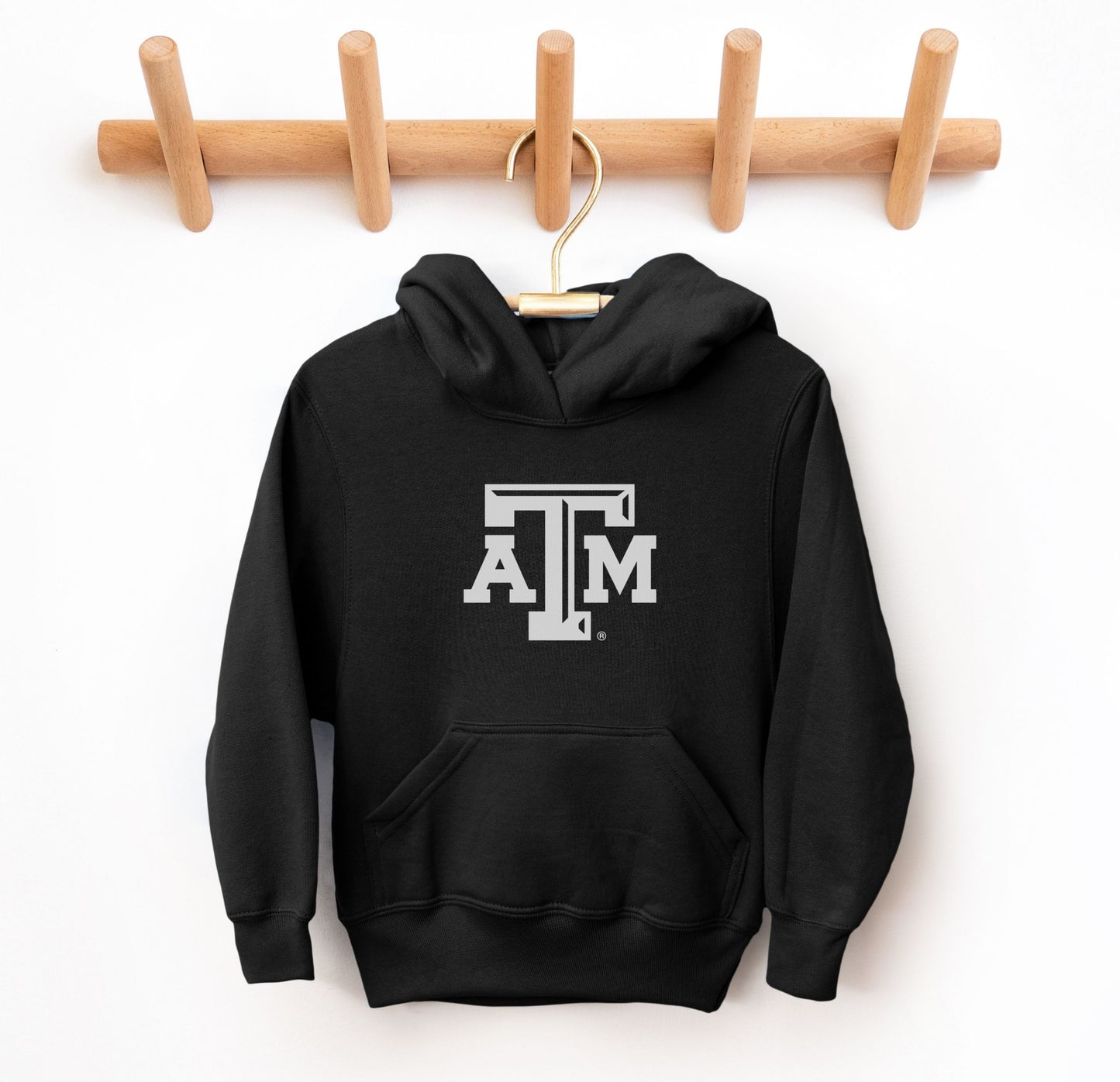 The Black Youth Unisex Texas A&M Logo Hooded Sweatshirt lays flat on a white background. The ﻿Texas A&M Logo﻿ graphic is in bold white in a Varsity style.