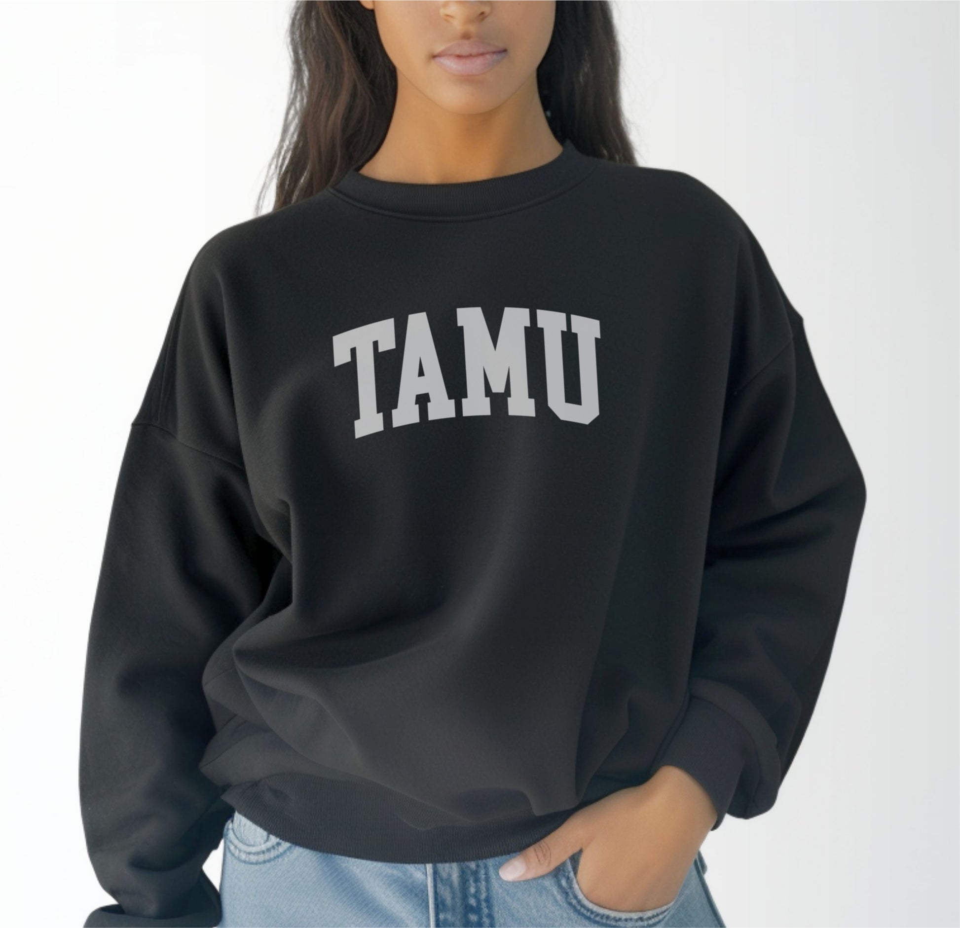 A model wears the Black Adult Unisex Texas A&M TAMU Crewneck Sweatshirt.  The ﻿Texas A&M TAMU﻿ graphic is in bold White in a Collegiate style.