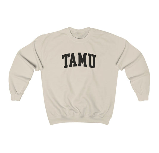 The Sand Adult Unisex Texas A&M TAMU Crewneck Sweatshirt lays flat on a white background. The ﻿Texas A&M TAMU﻿ graphic is in bold Black in a Collegiate style.