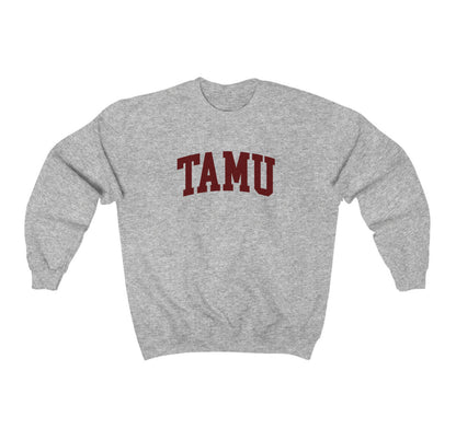 The Sport Grey Adult Unisex Texas A&M TAMU Crewneck Sweatshirt lays flat on a white background. The ﻿Texas A&M TAMU﻿ graphic is in bold Maroon in a Collegiate style.