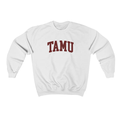 The White Adult Unisex Texas A&M TAMU Crewneck Sweatshirt lays flat on a white background. The ﻿Texas A&M TAMU﻿ graphic is in bold Maroon in a Collegiate style.