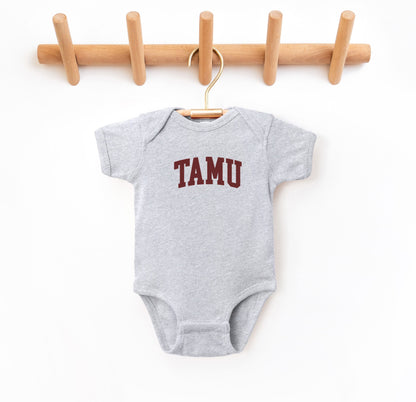 The Heather Grey Infant Unisex Texas A&M TAMU Bodysuit lays flat on a white background. The ﻿Texas A&M TAMU﻿ graphic is in bold Maroon in a Collegiate style.