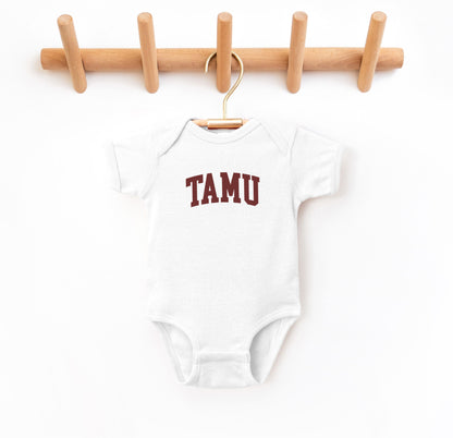 The White Infant Unisex Texas A&M TAMU Bodysuit lays flat on a white background. The ﻿Texas A&M TAMU﻿ graphic is in bold Maroon in a Collegiate style.