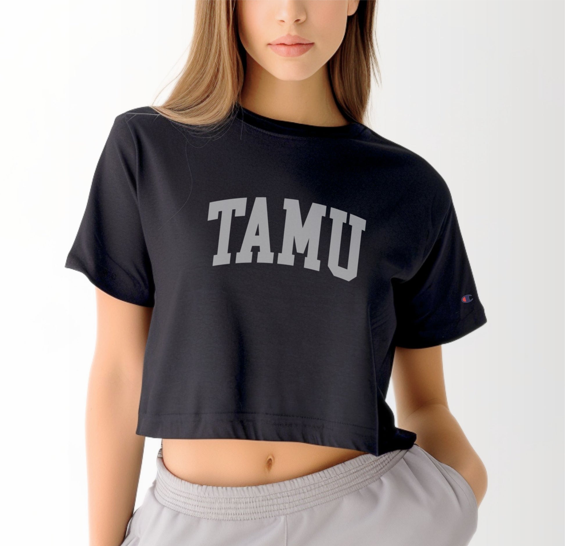 A model wears the Black Adult Womens Texas A&M TAMU Crop Top.  The ﻿Texas A&M TAMU﻿ graphic is in bold White in a Collegiate style.