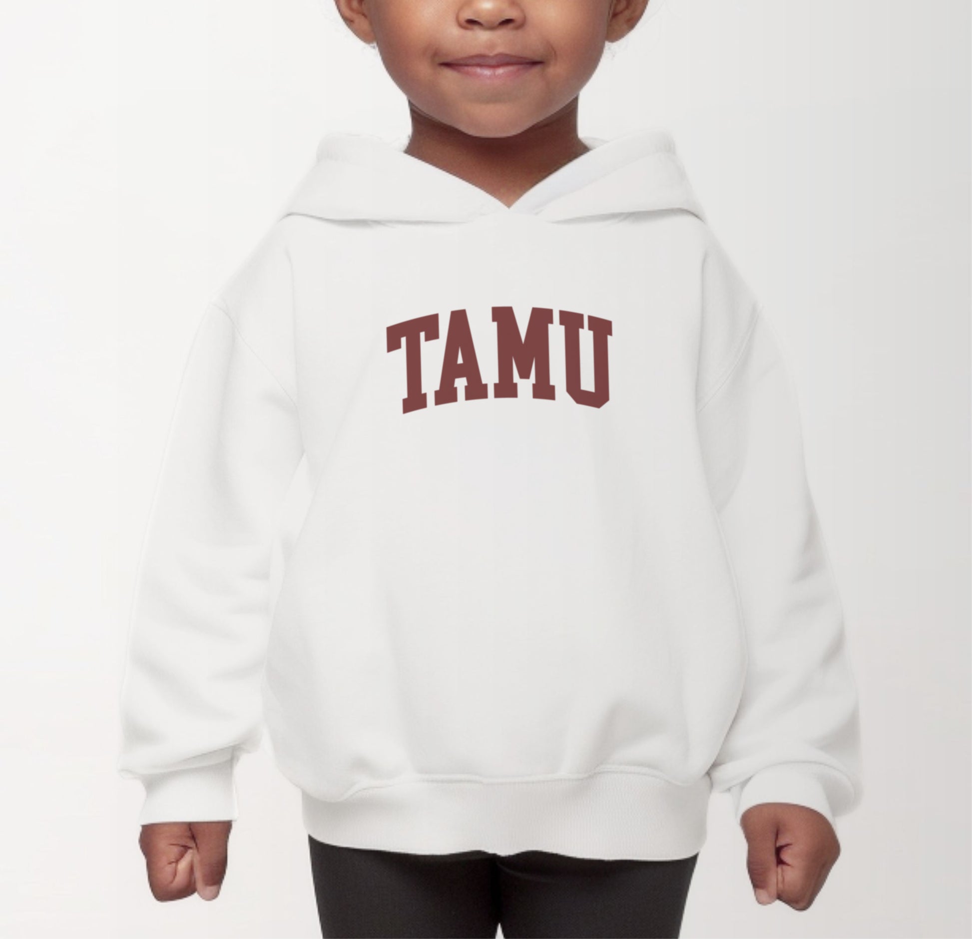 A model wears the White Toddler Unisex Texas A&M TAMU Hooded Sweatshirt.  The ﻿Texas A&M TAMU﻿ graphic is in bold Maroon in a Collegiate style.