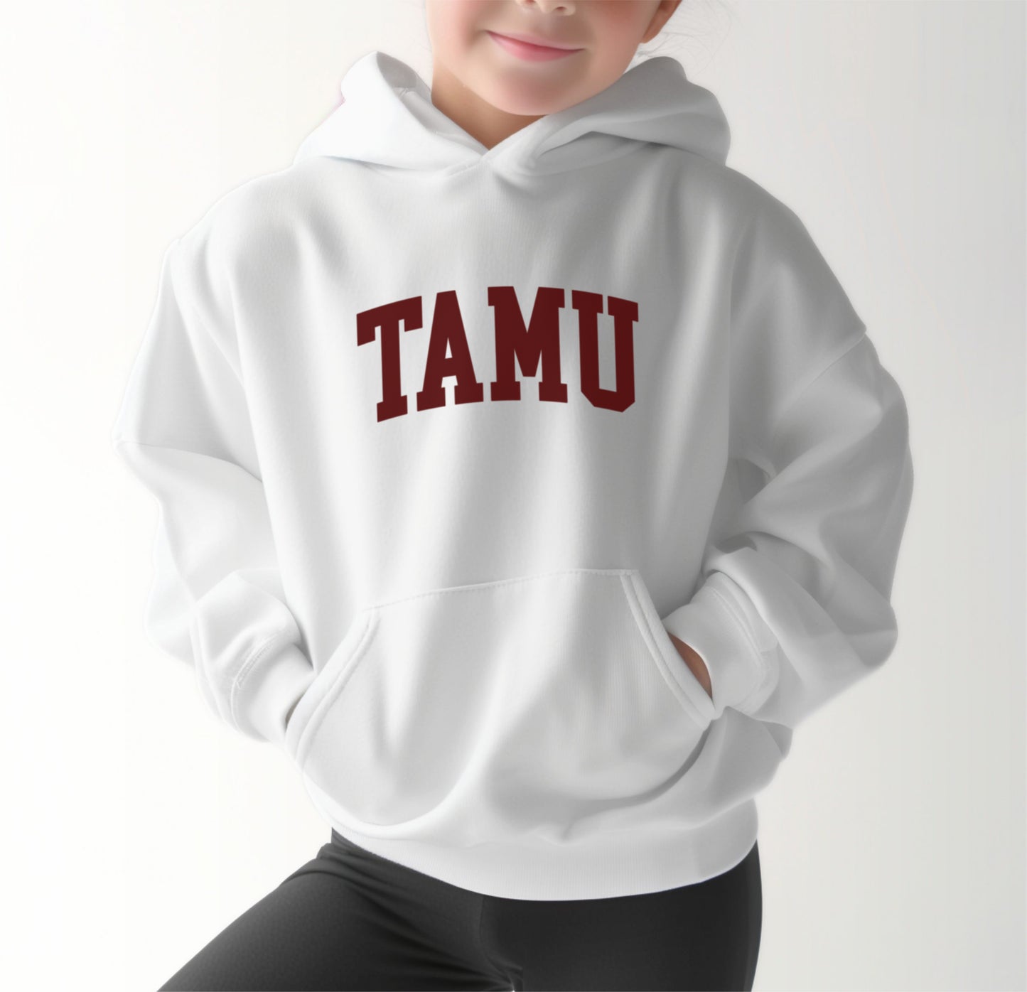 A model wears the White Youth Unisex Texas A&M TAMU Hooded Sweatshirt.  The ﻿Texas A&M TAMU﻿ graphic is in bold Maroon in a Collegiate style.