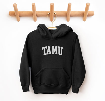 The Black Youth Unisex Texas A&M TAMU Hooded Sweatshirt lays flat on a white background. The ﻿Texas A&M TAMU﻿ graphic is in bold White in a Collegiate style.