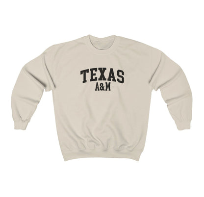 The Sand Adult Unisex Texas A&M Varsity Crewneck Sweatshirt lays flat on a white background. The ﻿Texas A&M Varsity﻿ graphic is in bold Black in a Collegiate style.