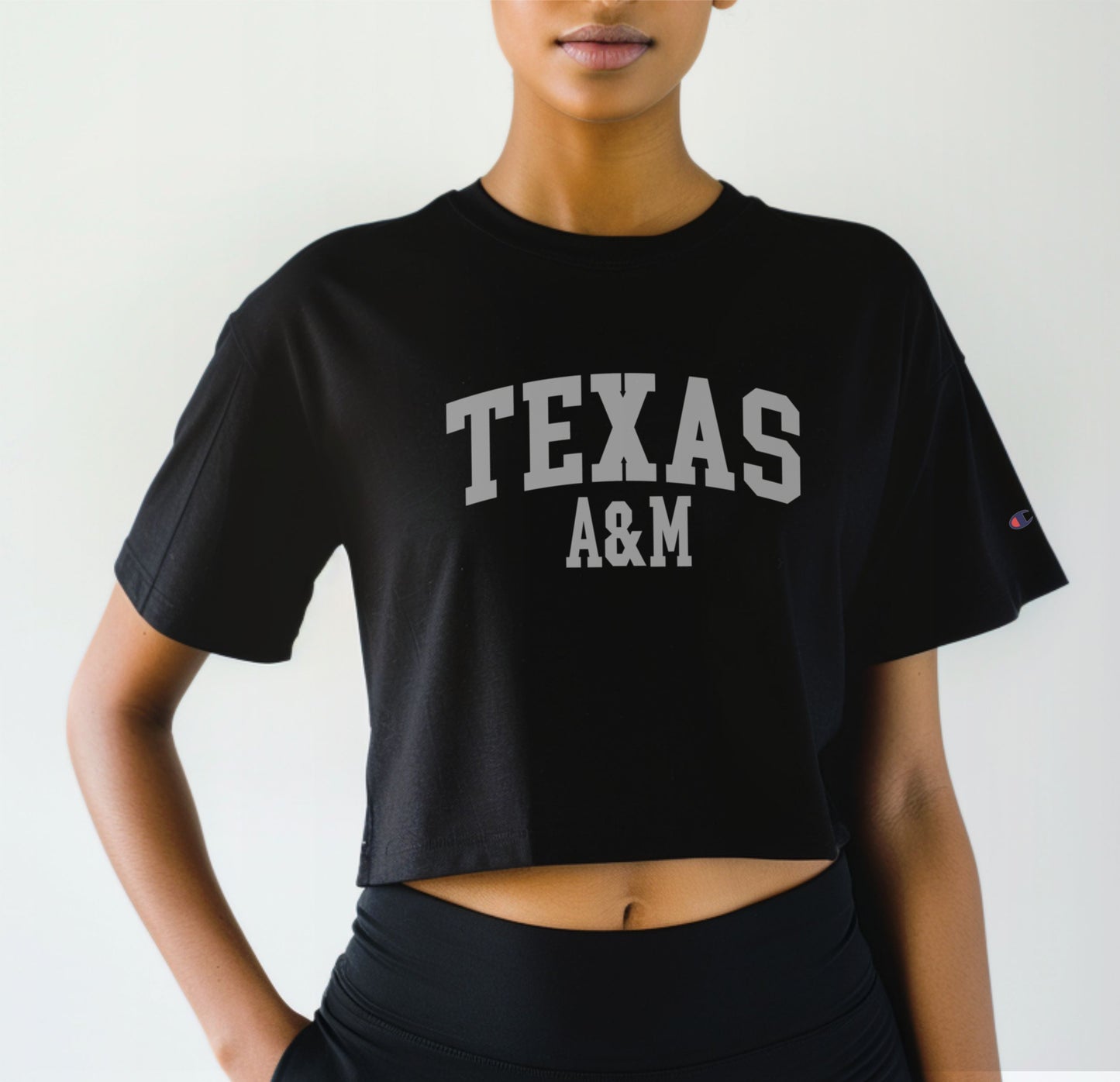 A model wears the Black Adult Womens Texas A&M Varsity Crop Top.  The ﻿Texas A&M Varsity﻿ graphic is in bold White in a Collegiate style.