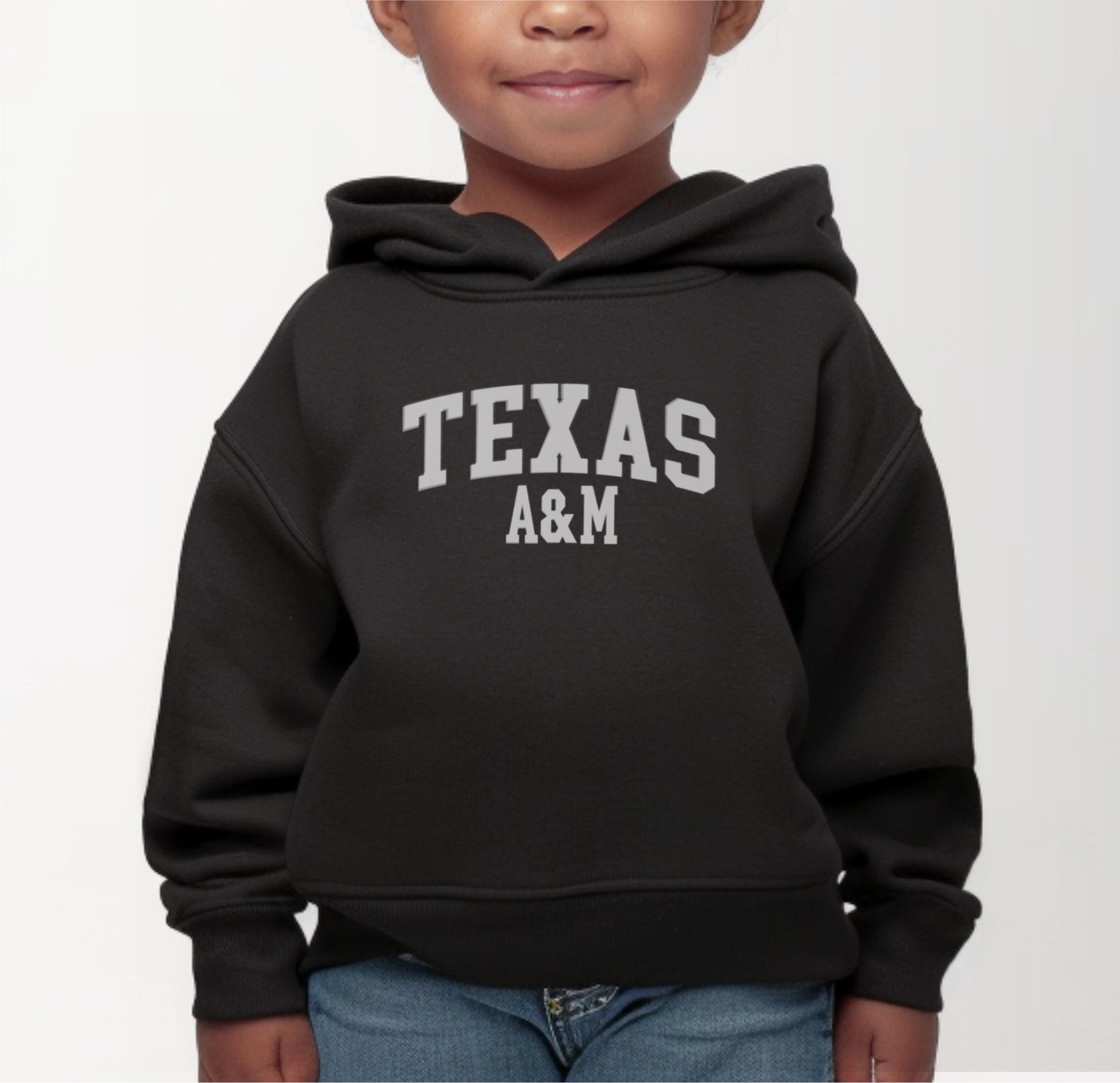 A model wears the Black Toddler Unisex Texas A&M Varsity Hooded Sweatshirt.  The ﻿Texas A&M Varsity﻿ graphic is in bold White in a Collegiate style.