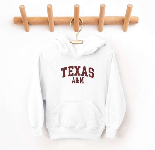 The White Youth Unisex Texas A&M Varsity Hooded Sweatshirt lays flat on a white background. The ﻿Texas A&M Varsity﻿ graphic is in bold Maroon in a Collegiate style.