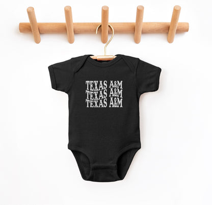 The Black Infant Unisex Texas A&M Western Bodysuit lays flat on a white background. The ﻿Texas A&M Western﻿ graphic is in bold White in a Western style.