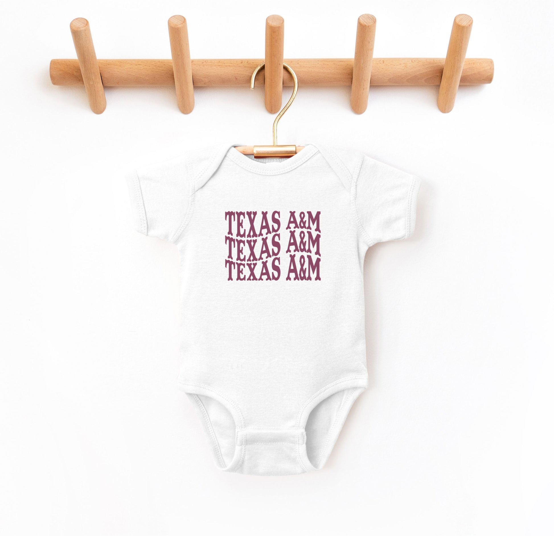 The White Infant Unisex Texas A&M Western Bodysuit lays flat on a white background. The ﻿Texas A&M Western﻿ graphic is in bold Maroon in a Western style.