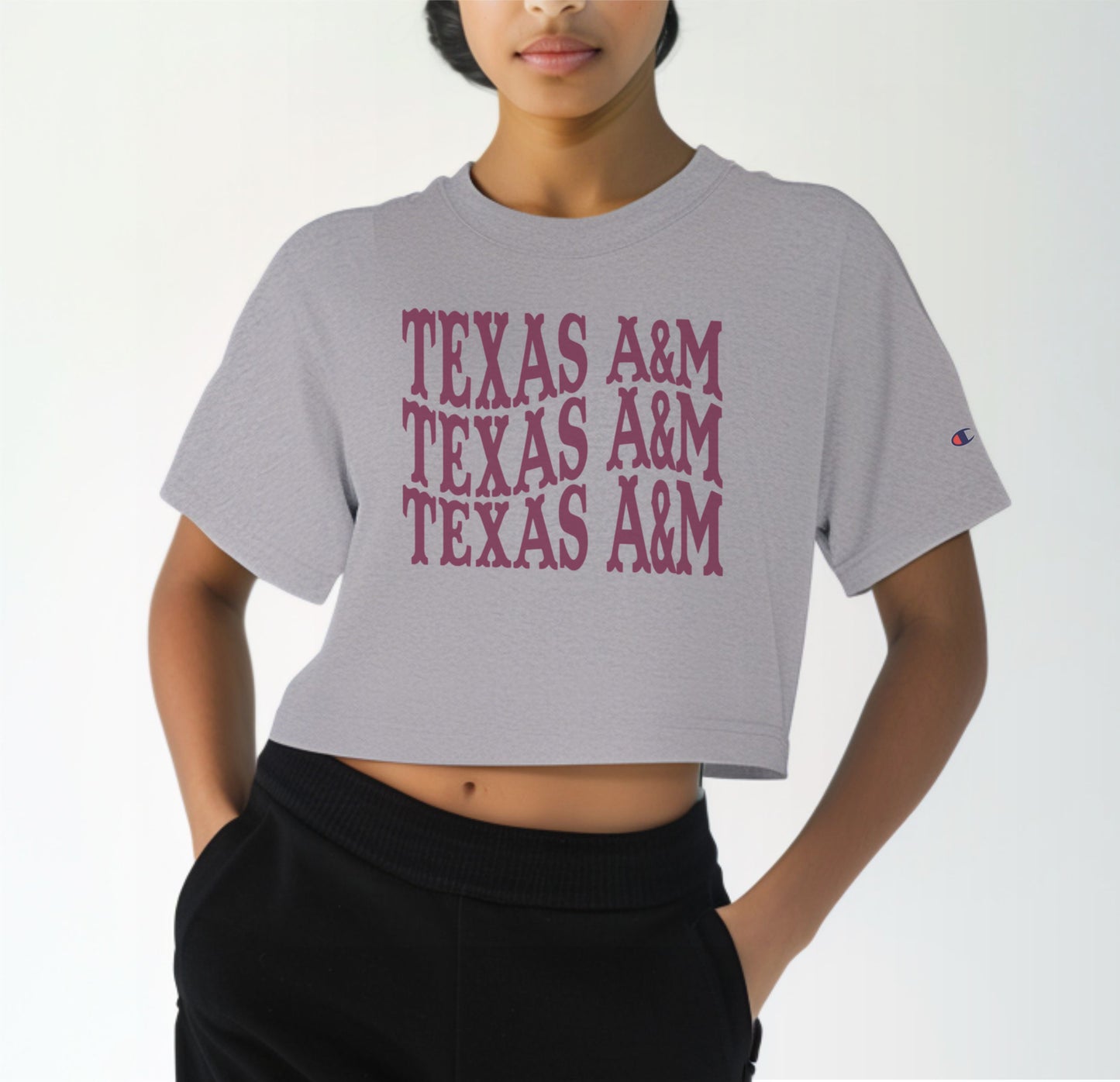 A model wears the Oxford Grey Adult Womens Texas A&M Western Crop Top.  The ﻿Texas A&M Western﻿ graphic is in bold Maroon in a Western style.