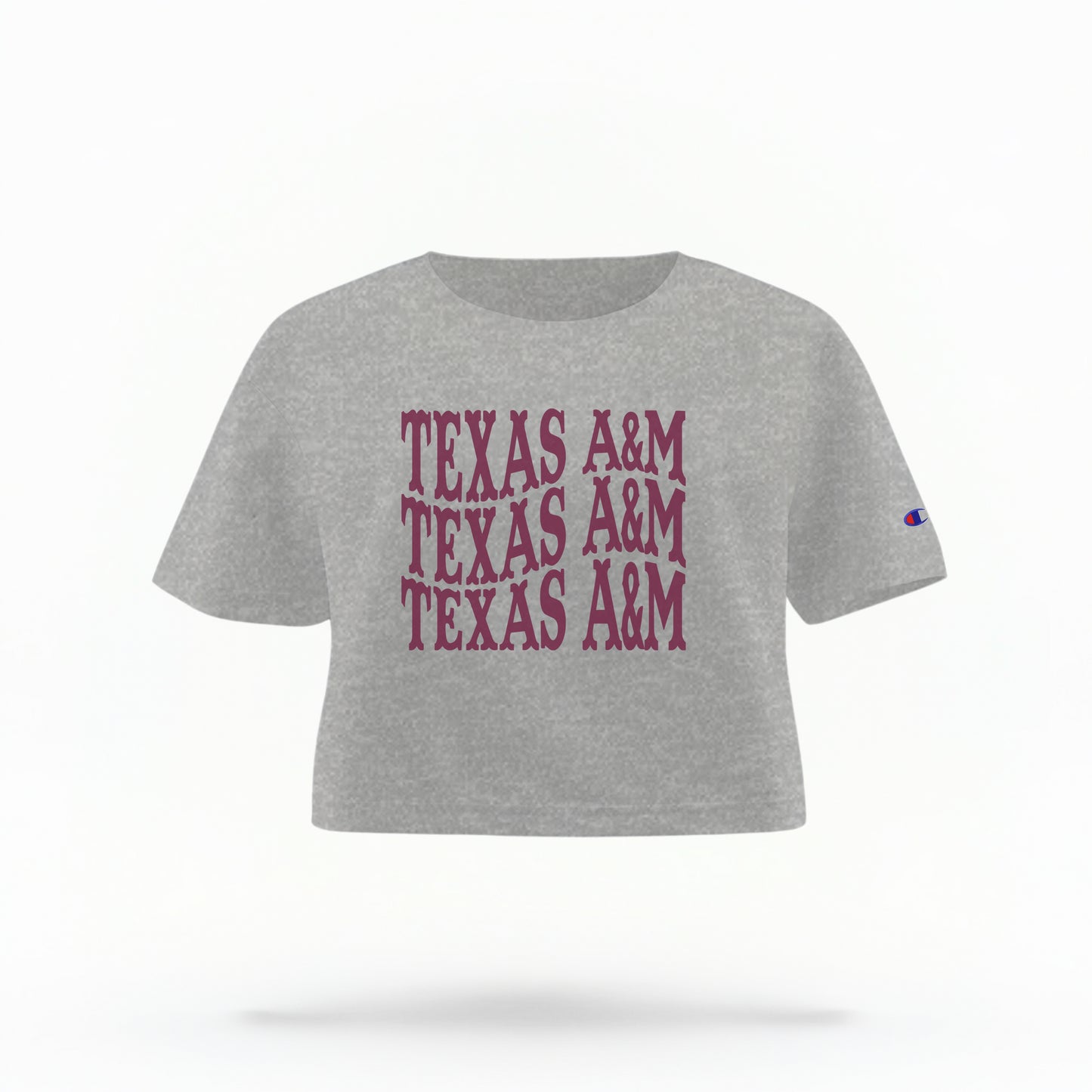 The Oxford Grey Adult Womens Texas A&M Western Crop Top lays flat on a white background. The ﻿Texas A&M Western﻿ graphic is in bold Maroon in a Western style.