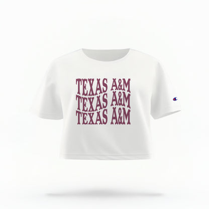 The White Adult Womens Texas A&M Western Crop Top lays flat on a white background. The ﻿Texas A&M Western﻿ graphic is in bold Maroon in a Western style.