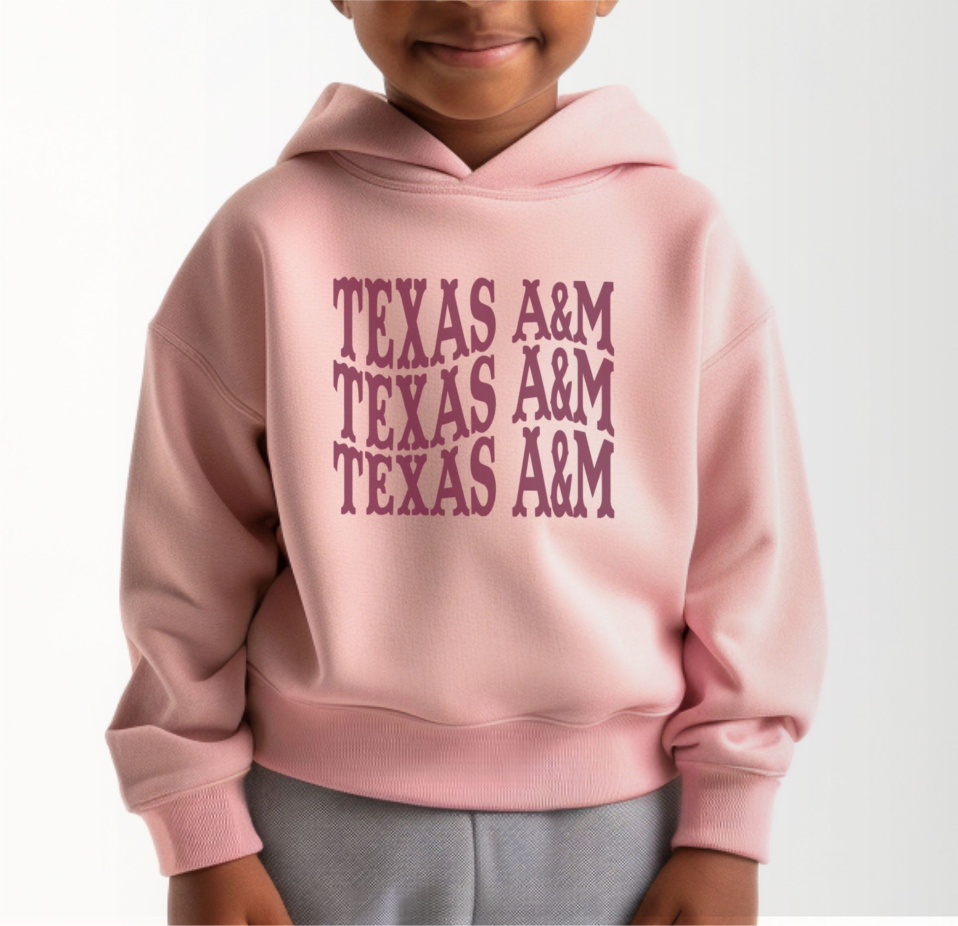 A model wears the Pink Toddler Unisex Texas A&M Western Hooded Sweatshirt.  The ﻿Texas A&M Western﻿ graphic is in bold White in a Western style.