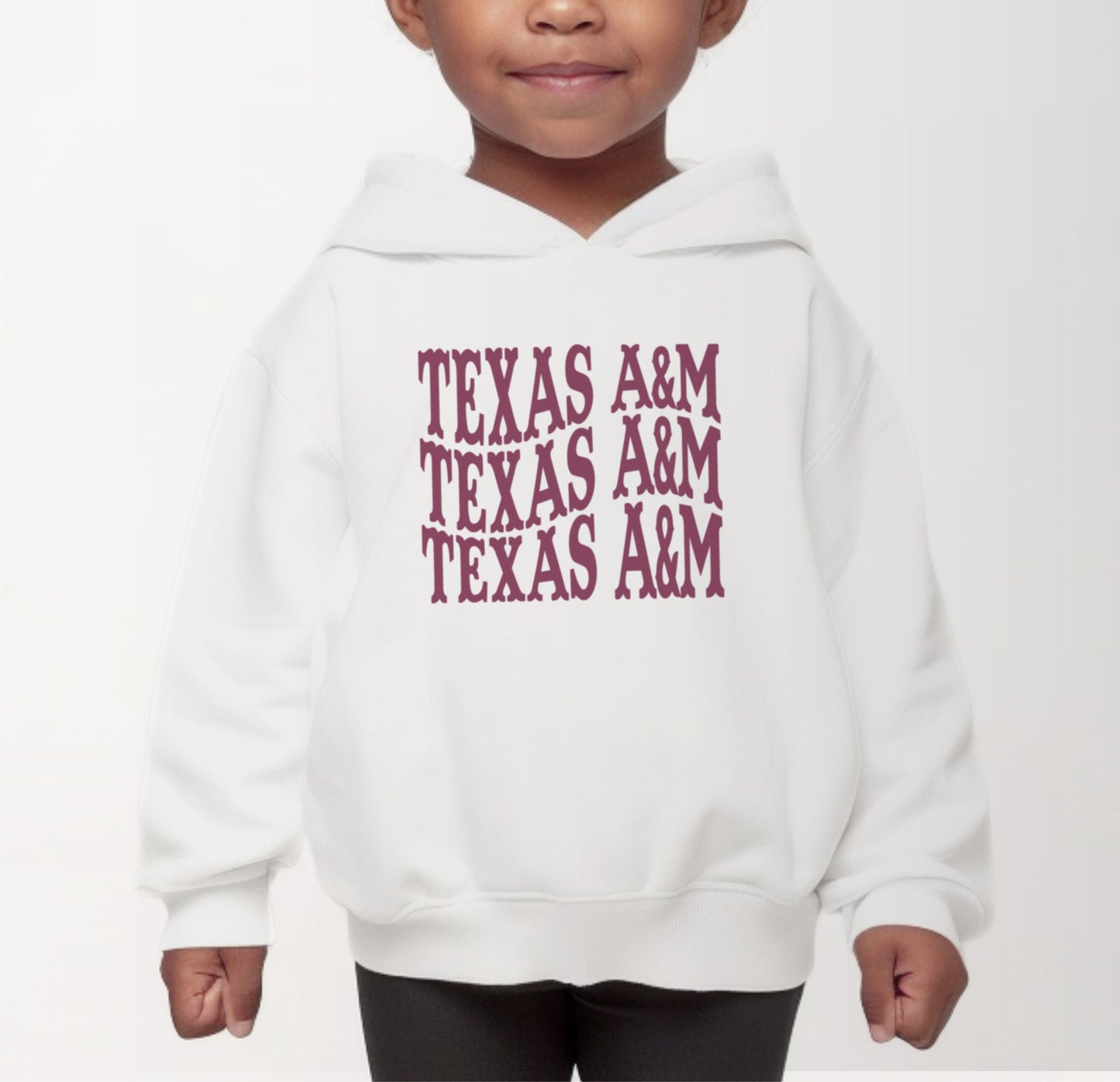 A model wears the White Toddler Unisex Texas A&M Western Hooded Sweatshirt.  The ﻿Texas A&M Western﻿ graphic is in bold Maroon in a Western style.