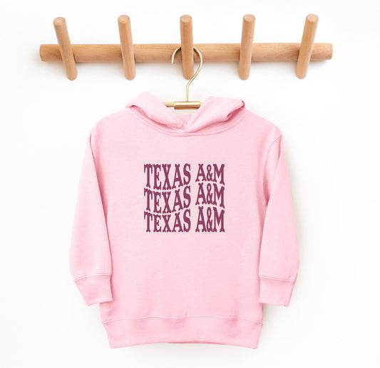 The Pink Toddler Unisex Texas A&M Western Hooded Sweatshirt lays flat on a white background. The ﻿Texas A&M Western﻿ graphic is in bold White in a Western style.