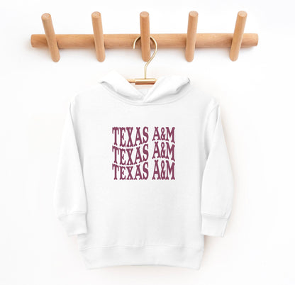 The White Toddler Unisex Texas A&M Western Hooded Sweatshirt lays flat on a white background. The ﻿Texas A&M Western﻿ graphic is in bold Maroon in a Western style.