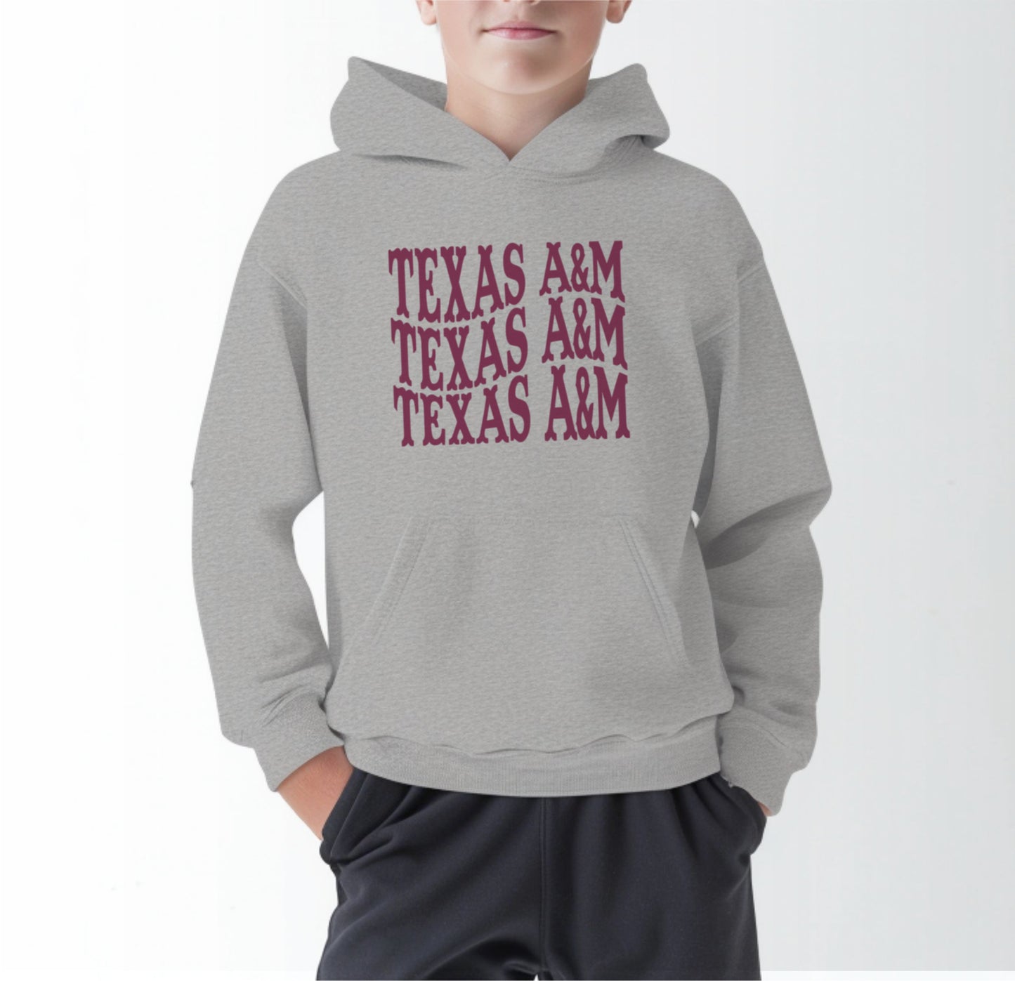 A model wears the Sport Grey Youth Unisex Texas A&M Western Hooded Sweatshirt.  The ﻿Texas A&M Western﻿ graphic is in bold Maroon in a Western style.