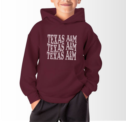 A model wears the Maroon Youth Unisex Texas A&M Western Hooded Sweatshirt.  The ﻿Texas A&M Western﻿ graphic is in bold White in a Western style.