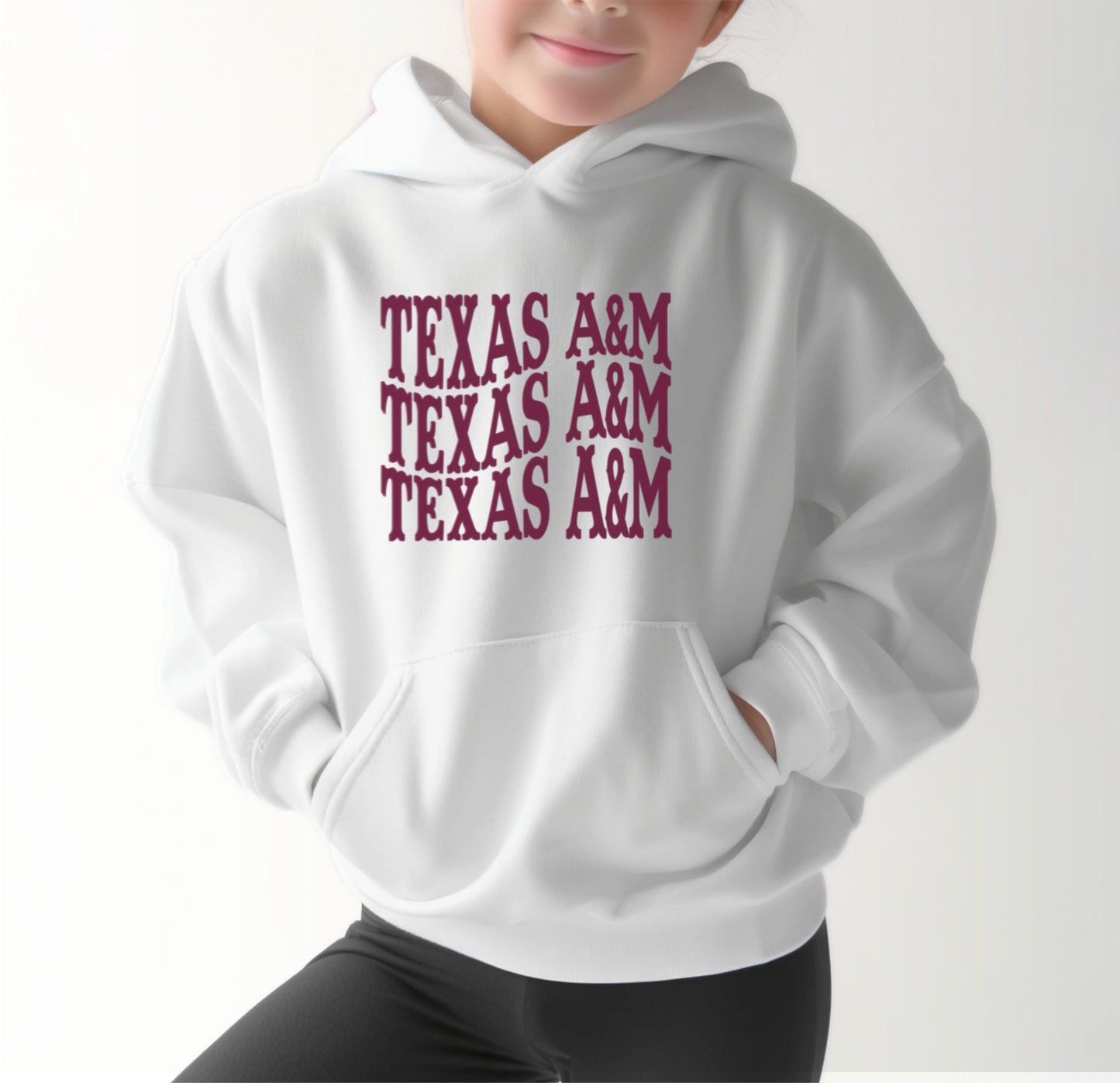 A model wears the White Youth Unisex Texas A&M Western Hooded Sweatshirt.  The ﻿Texas A&M Western﻿ graphic is in bold Maroon in a Western style.