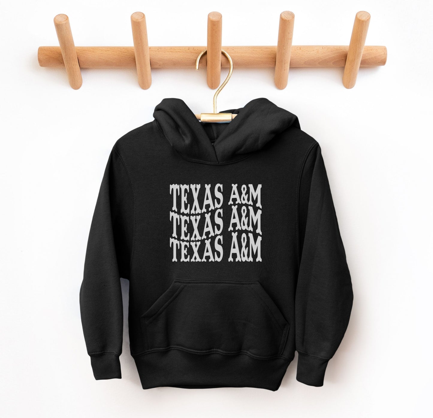 The Black Youth Unisex Texas A&M Western Hooded Sweatshirt lays flat on a white background. The ﻿Texas A&M Western﻿ graphic is in bold White in a Western style.