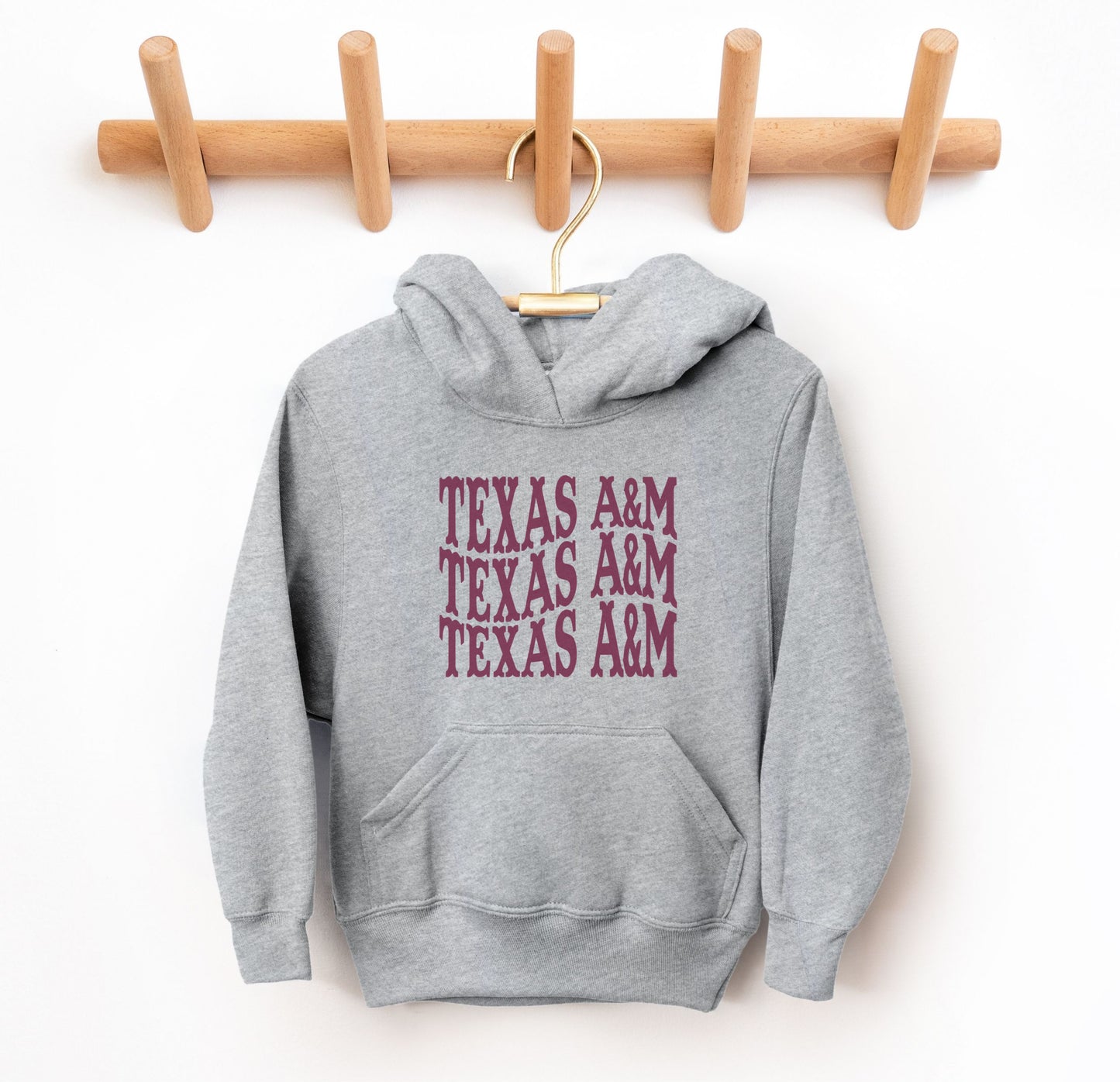 The Grey Youth Unisex Texas A&M Western Hooded Sweatshirt lays flat on a white background. The ﻿Texas A&M Western﻿ graphic is in bold Maroon in a Western style.