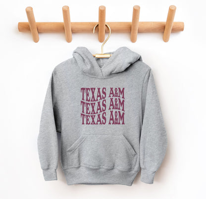 The Grey Youth Unisex Texas A&M Western Hooded Sweatshirt lays flat on a white background. The ﻿Texas A&M Western﻿ graphic is in bold Maroon in a Western style.