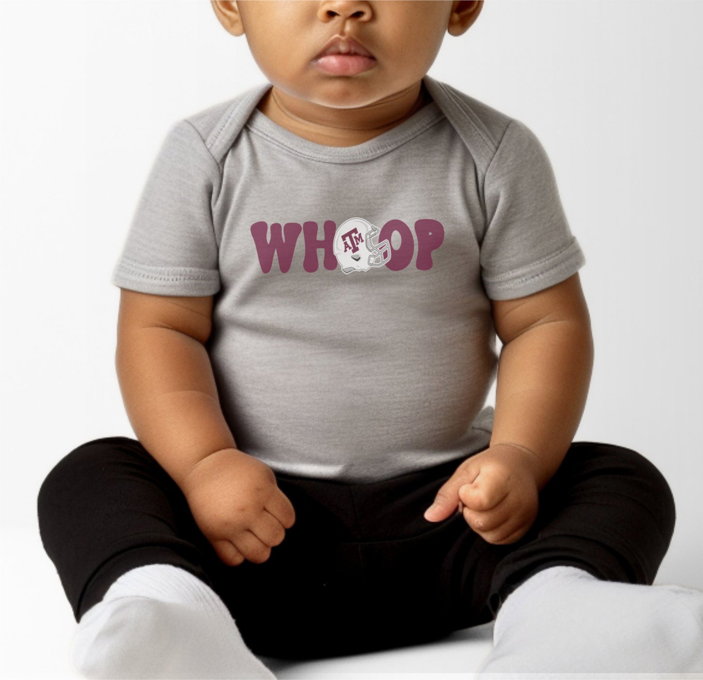 A model wears the Black Infant Unisex Texas A&M Retro Whoop Bodysuit.  The ﻿Texas A&M Retro Whoop﻿ graphic is in bold White in a Vintage style.