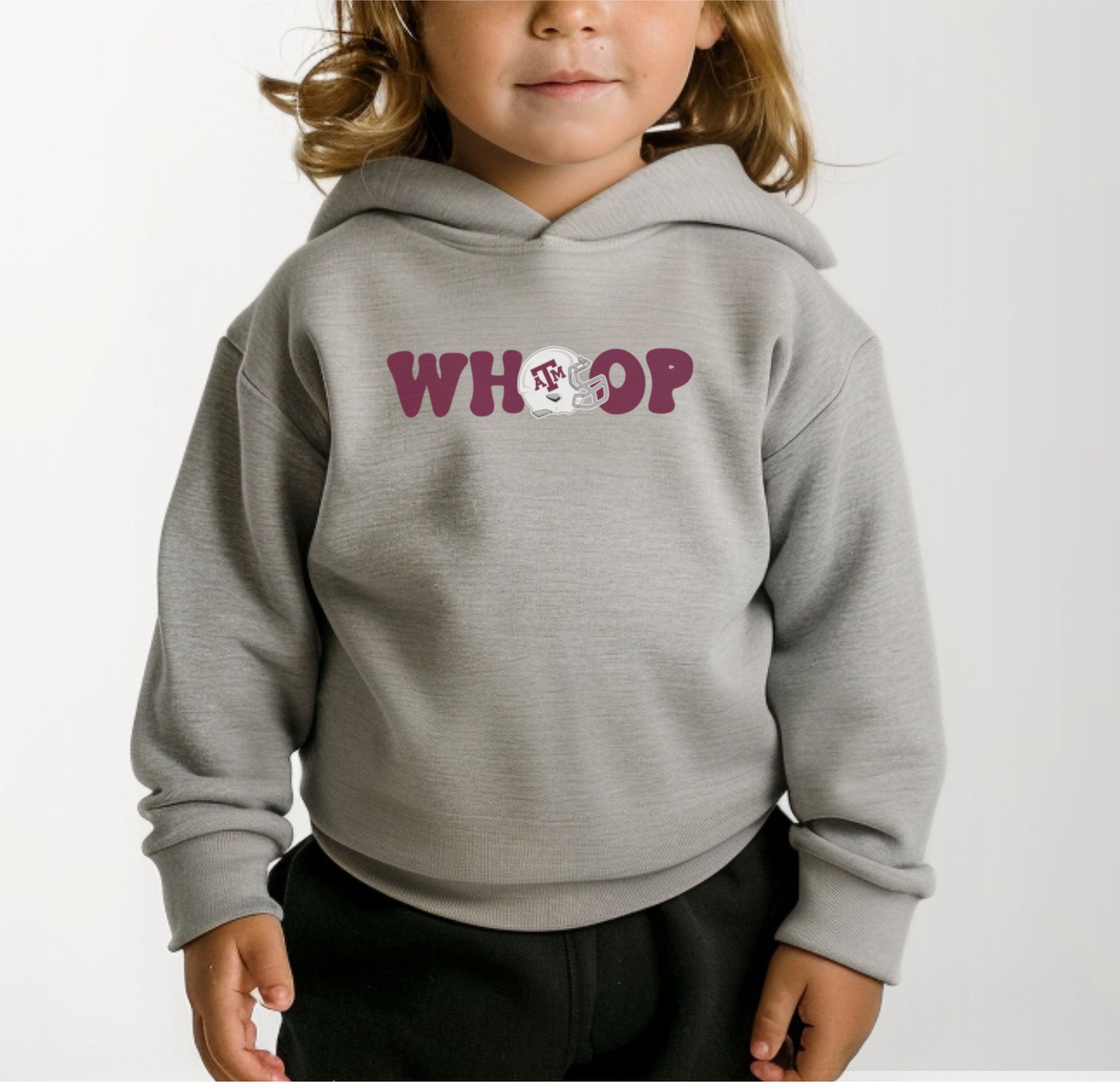 A model wears the Heather Grey Toddler Unisex Texas A&M Retro Whoop Hooded Sweatshirt.  The ﻿Texas A&M Retro Whoop﻿ graphic is in bold Maroon in a Vintage style.