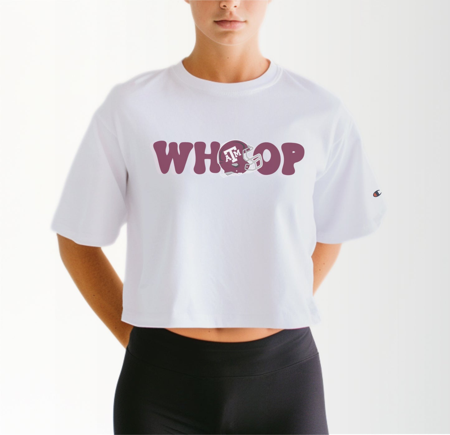 A model wears the White Adult Womens Texas A&M Retro Whoop Crop Top.  The ﻿Texas A&M Retro Whoop﻿ graphic is in bold Maroon in a Vintage style.