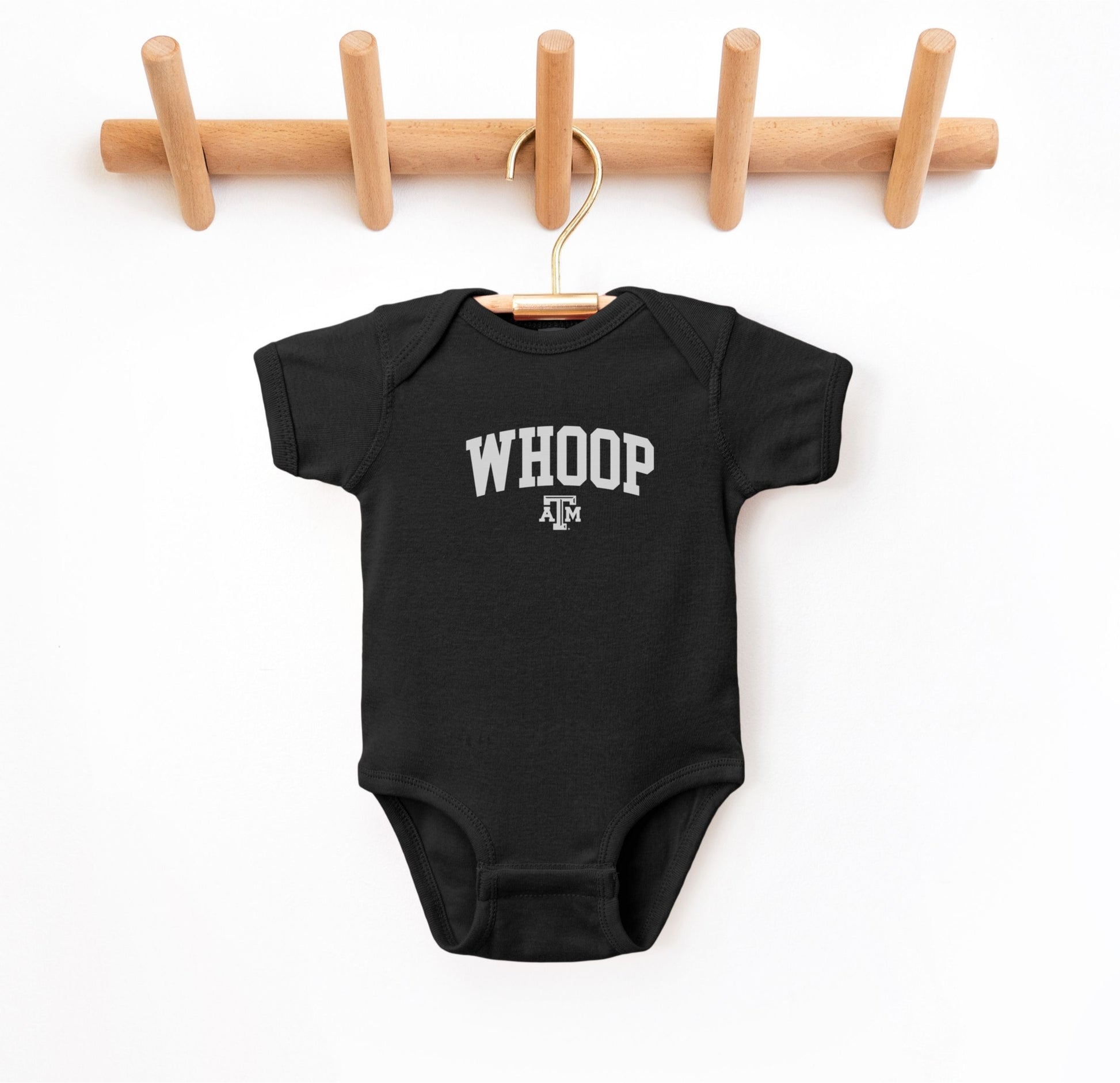 The Black Infant Unisex Texas A&M Whoop Collegiate Bodysuit lays flat on a white background. The ﻿Texas A&M Whoop Collegiate﻿ graphic is in bold White in a Varsity style.