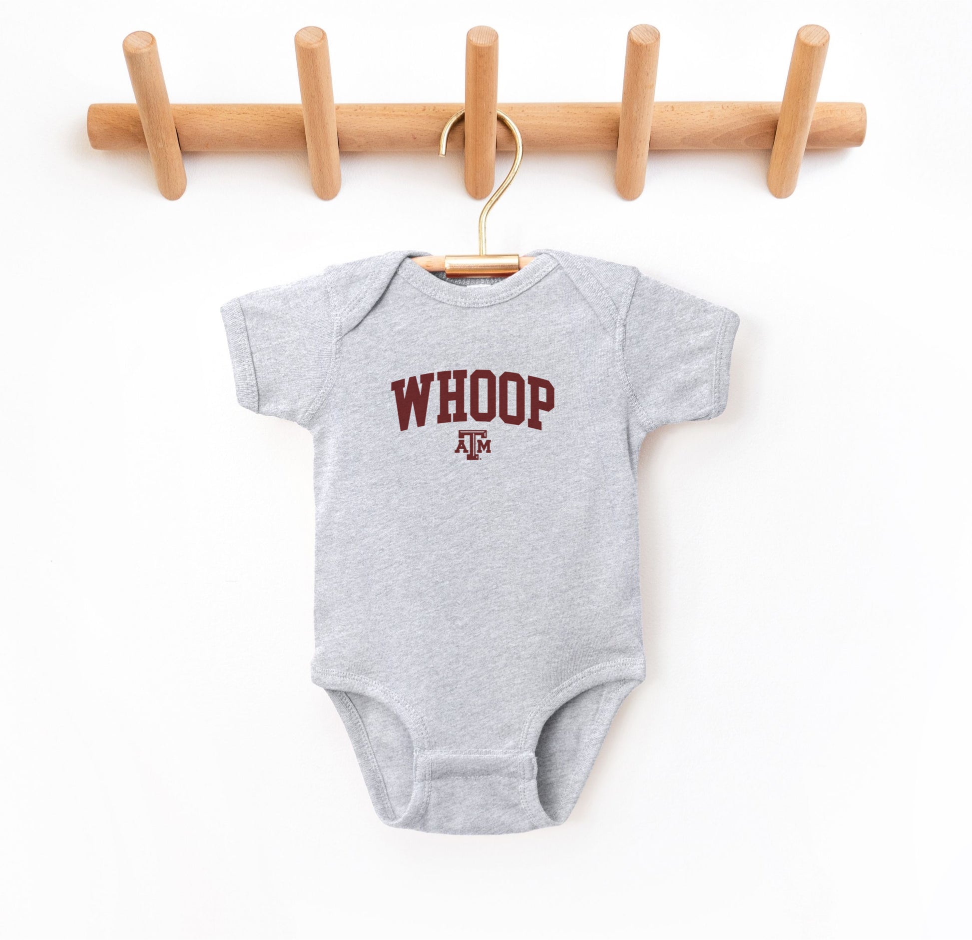 The Heather Grey Infant Unisex Texas A&M Whoop Collegiate Bodysuit lays flat on a white background. The ﻿Texas A&M Whoop Collegiate﻿ graphic is in bold Maroon in a Varsity style.