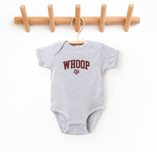 The Heather Grey Infant Unisex Texas A&M Whoop Collegiate Bodysuit lays flat on a white background. The ﻿Texas A&M Whoop Collegiate﻿ graphic is in bold Maroon in a Varsity style.